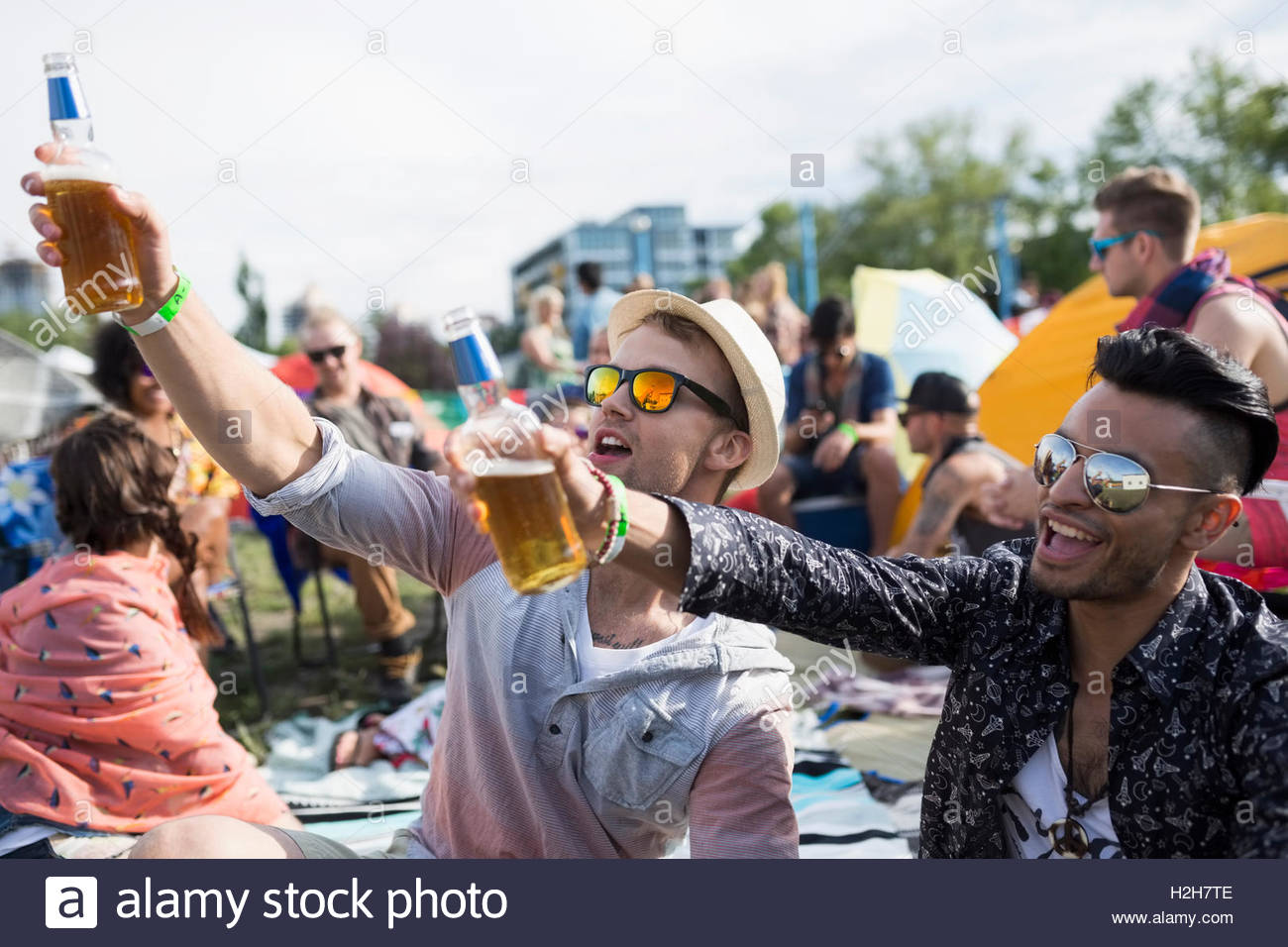 I giovani uomini a bere birra rasserenante al festival musicale estivo Campeggio Foto Stock