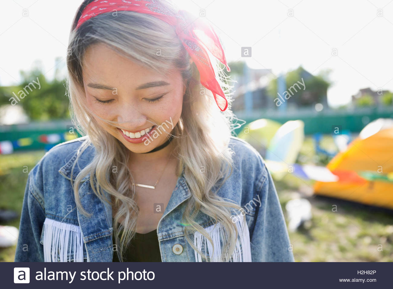 Ritratto sorridente giovane donna guardando giù al festival musicale estivo Campeggio Foto Stock