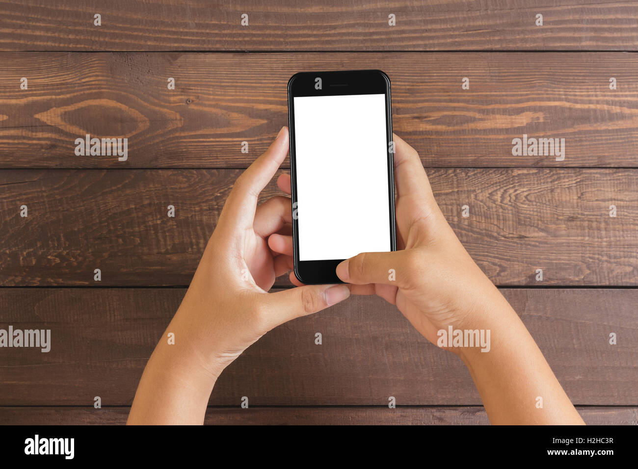 Il telefono in mano la donna che mostra lo schermo bianco su tavola di legno, mockup nuovo stile di telefono a getto di colore nero Foto Stock