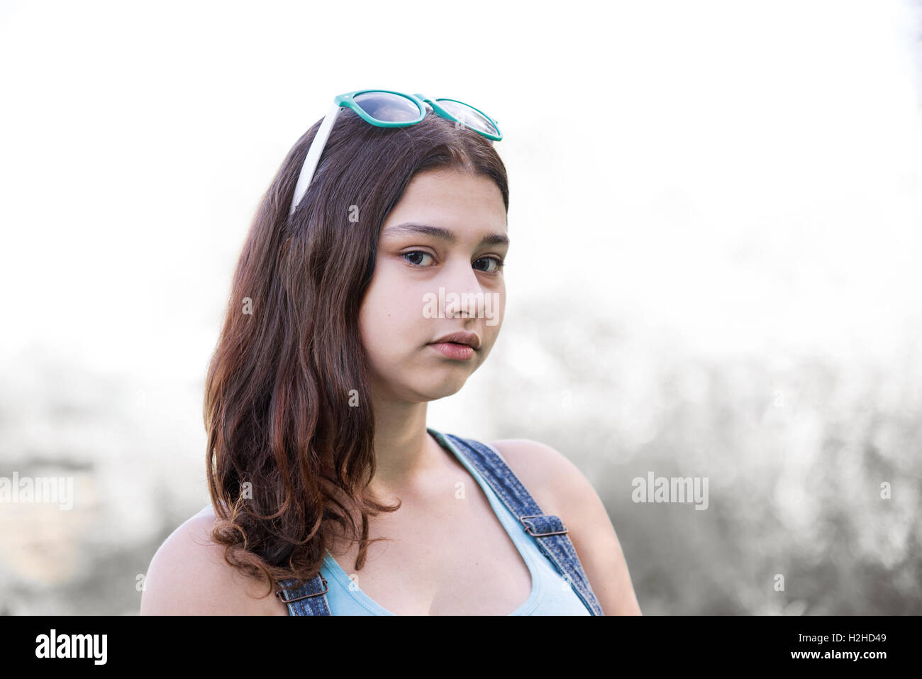 La ragazza con gli occhiali da sole sul suo capo in posa nella natura, tonica immagine Foto Stock