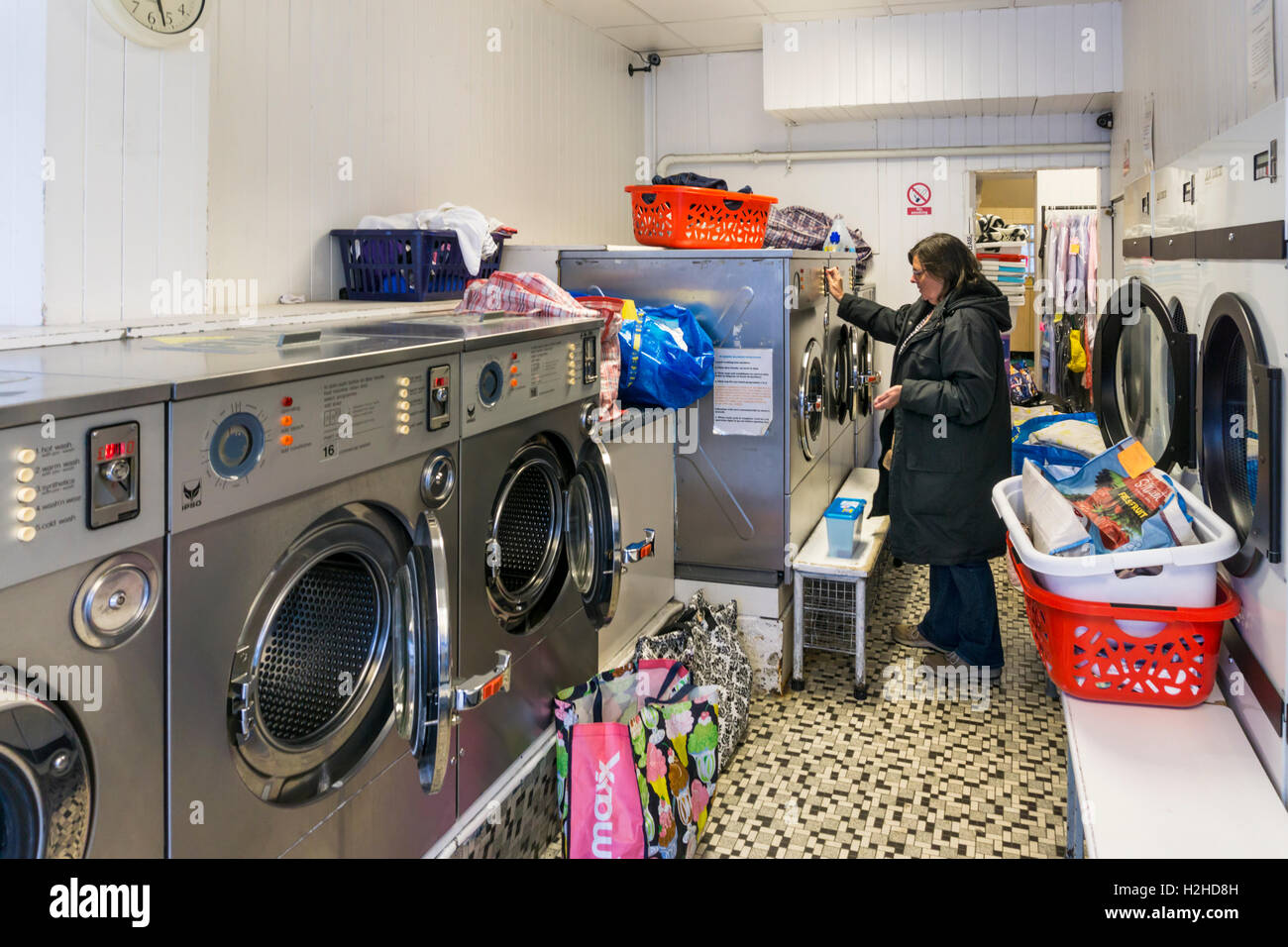 Donna che utilizza una gettoniera self-service di macchina di lavaggio in una lavanderia a gettoni. Foto Stock