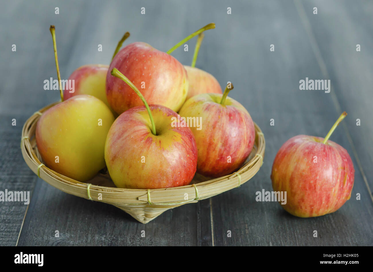Rosso e giallo apple con cesto di bambù , organica frutta fresca su sfondo di legno Foto Stock