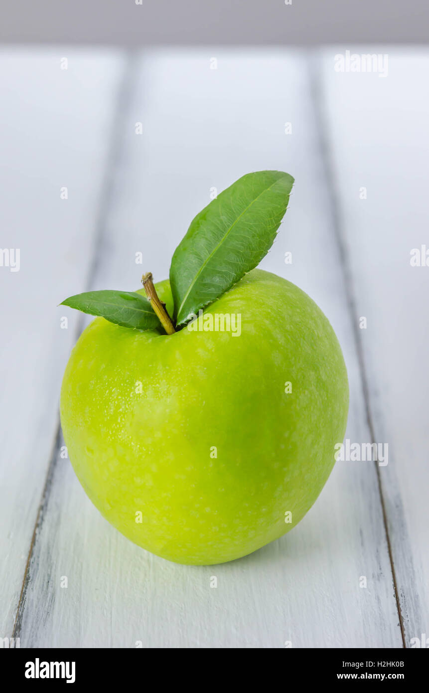Mature mela verde con foglie su un sfondo di legno Foto Stock
