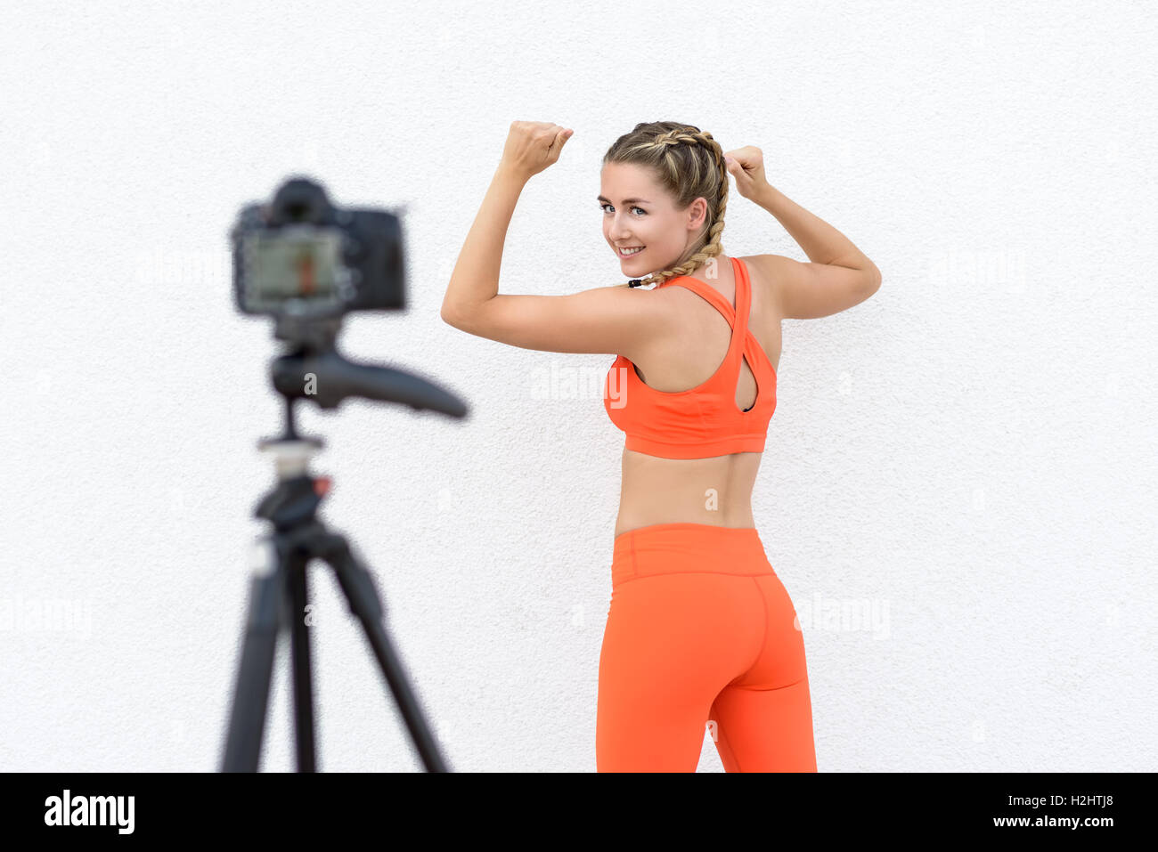 Giovani blogger fitness prendendo un selfie video come lei dimostra vari esercizi per uno stile di vita più sano in posa di fronte a una Foto Stock