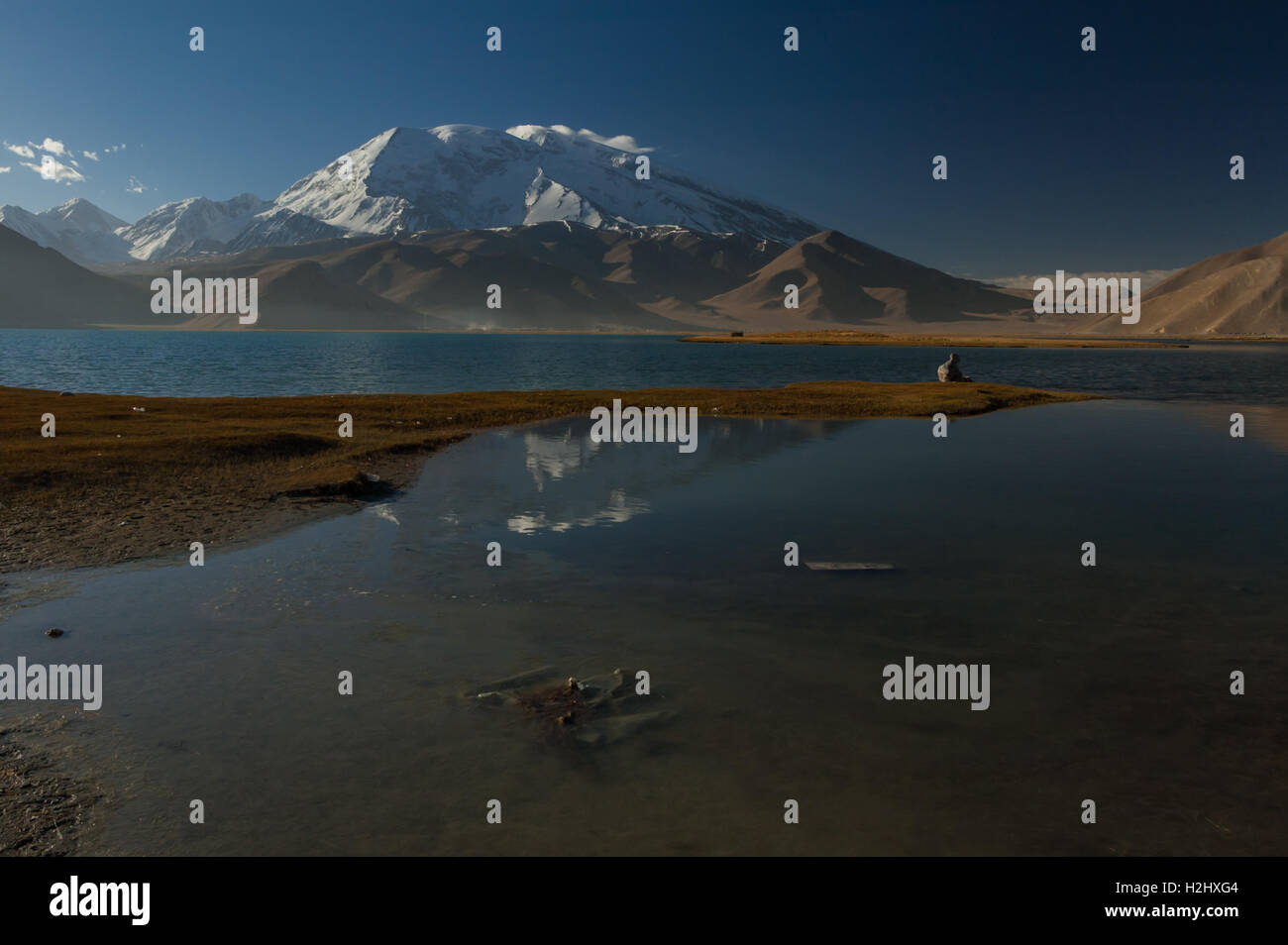 Snow capped Muztagh Ata mountain si riflette nelle acque del Lago Karakul sulla Karakoram Highway, Xinjiang. Foto Stock