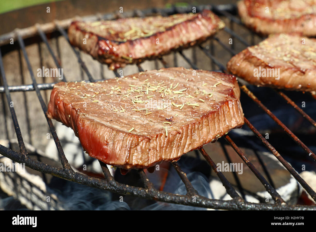 Sizzling grigliate di carni bovine bistecche grigliate con spezie preparato di cottura sulla griglia per il barbecue, close up Foto Stock