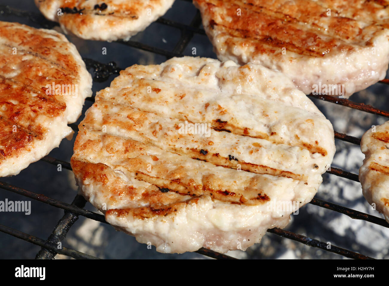 Pollo o tacchino carne di pollame barbecue hamburger grigliati per hamburger preparati sul fumo barbecue grill, close up Foto Stock