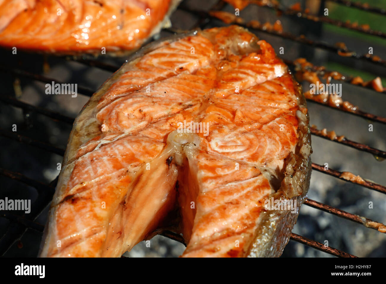 Una grigliata di pesce Salmone bistecca pasto barbecue per la cottura, preparato sulla griglia per il barbecue, close up Foto Stock