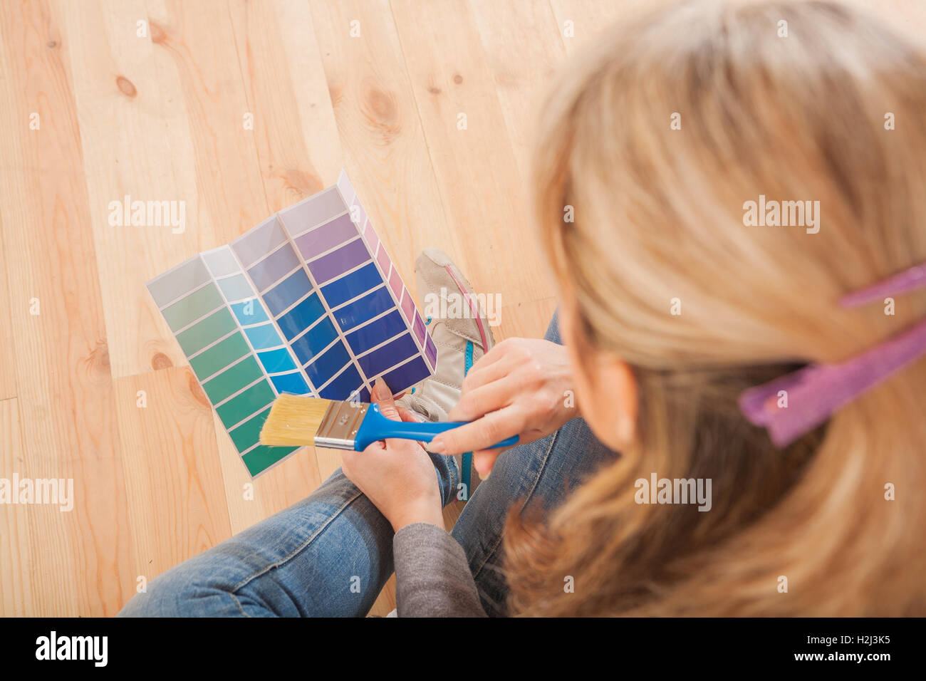 Pittore femmina seduto sul pavimento e alla ricerca sulla tavolozza dei colori Foto Stock