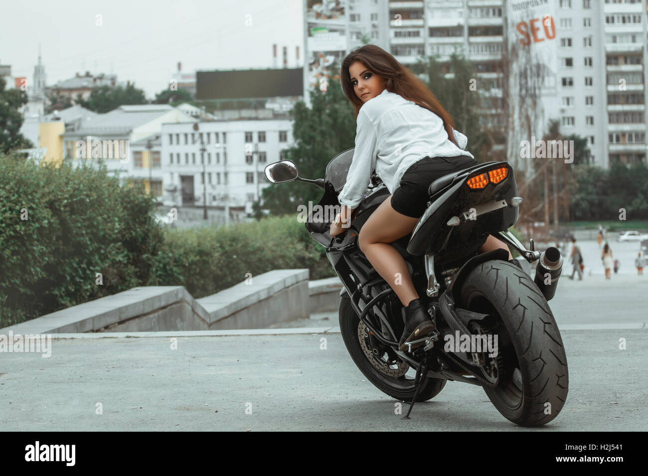 Biker ragazza scorre una motocicletta sotto la pioggia. Visuale in prima persona Foto Stock