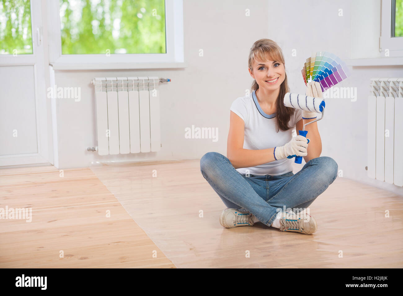 Bella donna sorridente lavoratore seduto sul pavimento in legno e visualizza Foto Stock
