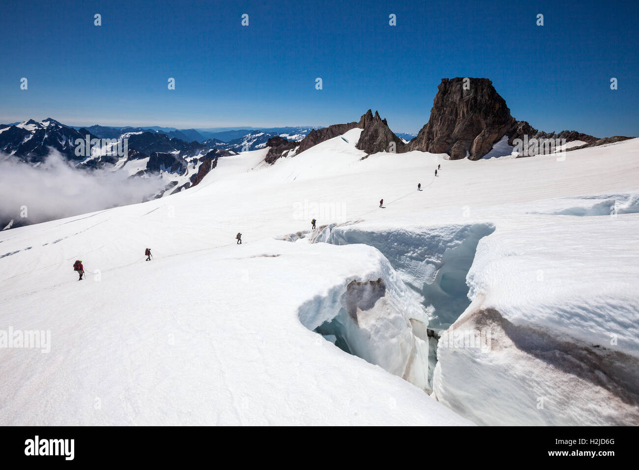 Due corda-team di alpinisti di attraversamento di un crepaccio sul ghiacciaio picco nel North Cascades montagne, nello Stato di Washington, USA Foto Stock