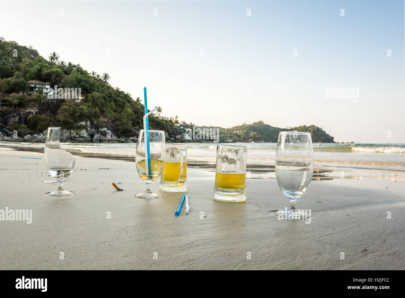 Inquinamento sulla spiaggia. Pericolo! Rotture di birra e liquori di vetro con paglia a sinistra nella sabbia Foto Stock