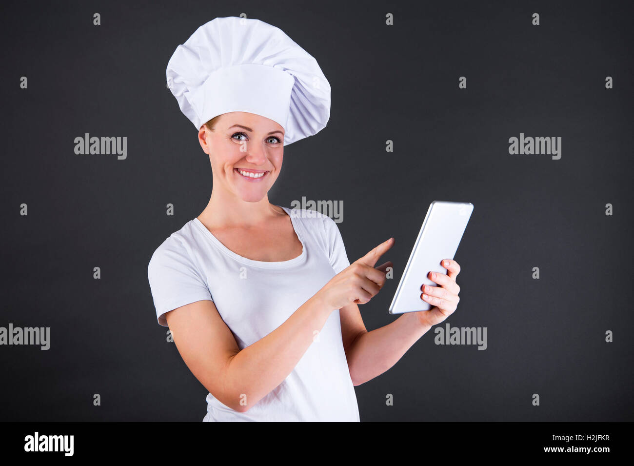 La cottura, la tecnologia e il concetto di cibo - femmina sorridente chef cuoco o baker con tablet pc computer Foto Stock