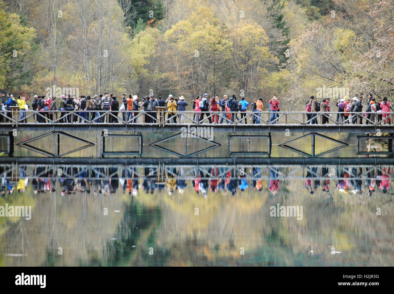 La riflessione di turisti cinesi in piedi sul ponte a cinque fiore Lago, Jiuzhaigou Parco Nazionale, Cina. Foto Stock