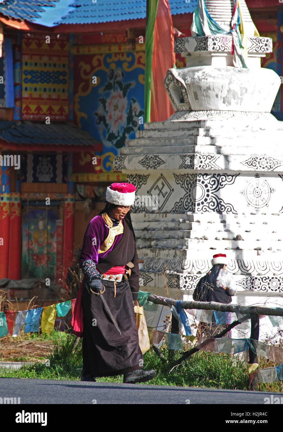 Un anziano tibetano lady va circa la sua routine mattutina in Jiuzhaigou Parco Nazionale, Cina. Foto Stock