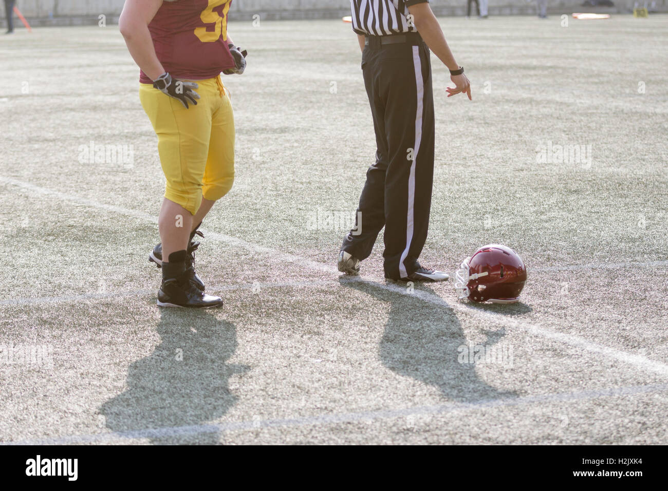 Giocatore di football americano, arbitro e casco sul campo Foto Stock
