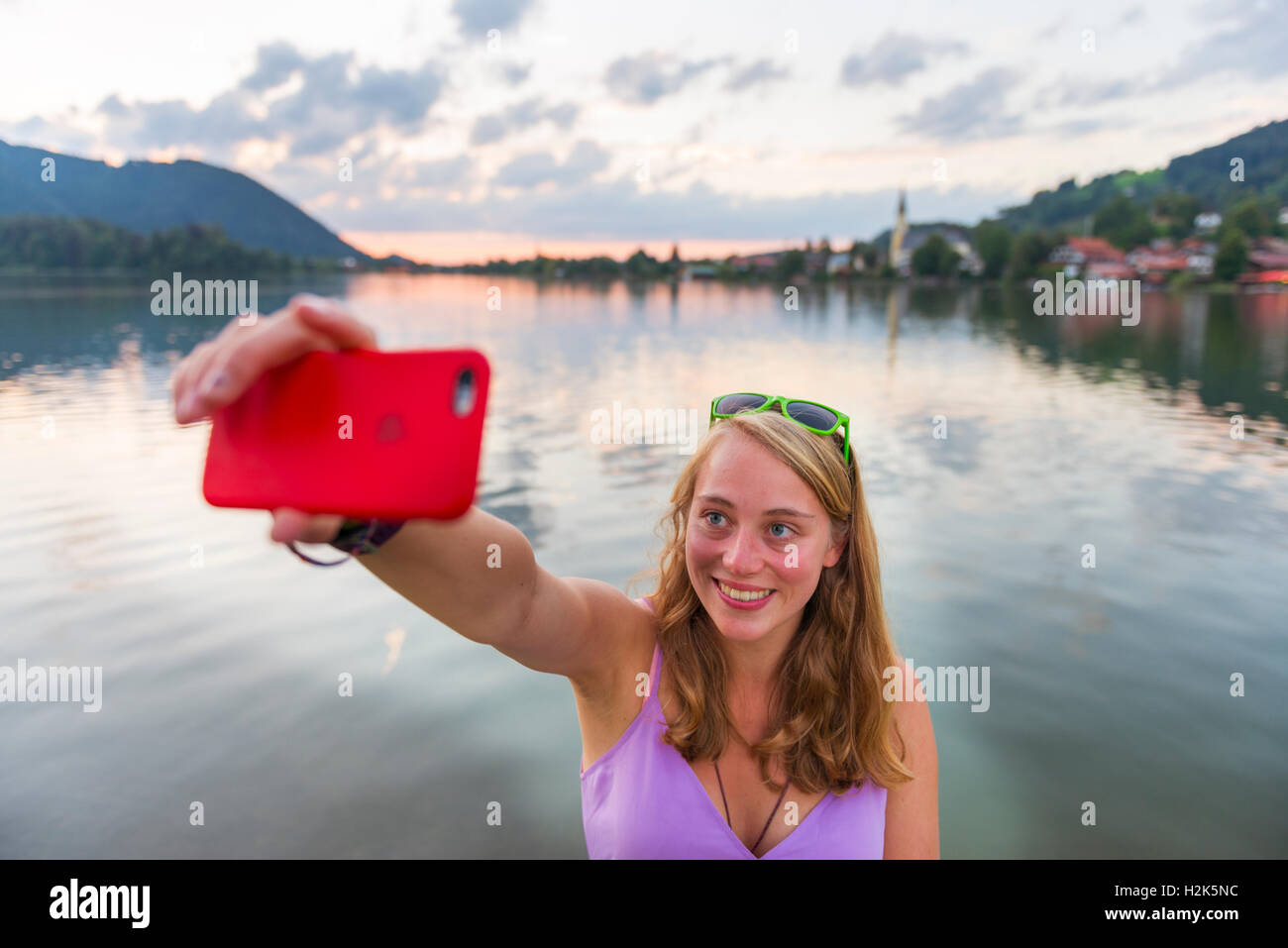 Giovane donna prendendo un selfie e sorridente, Schliersee, Alta Baviera, Baviera, Germania Foto Stock