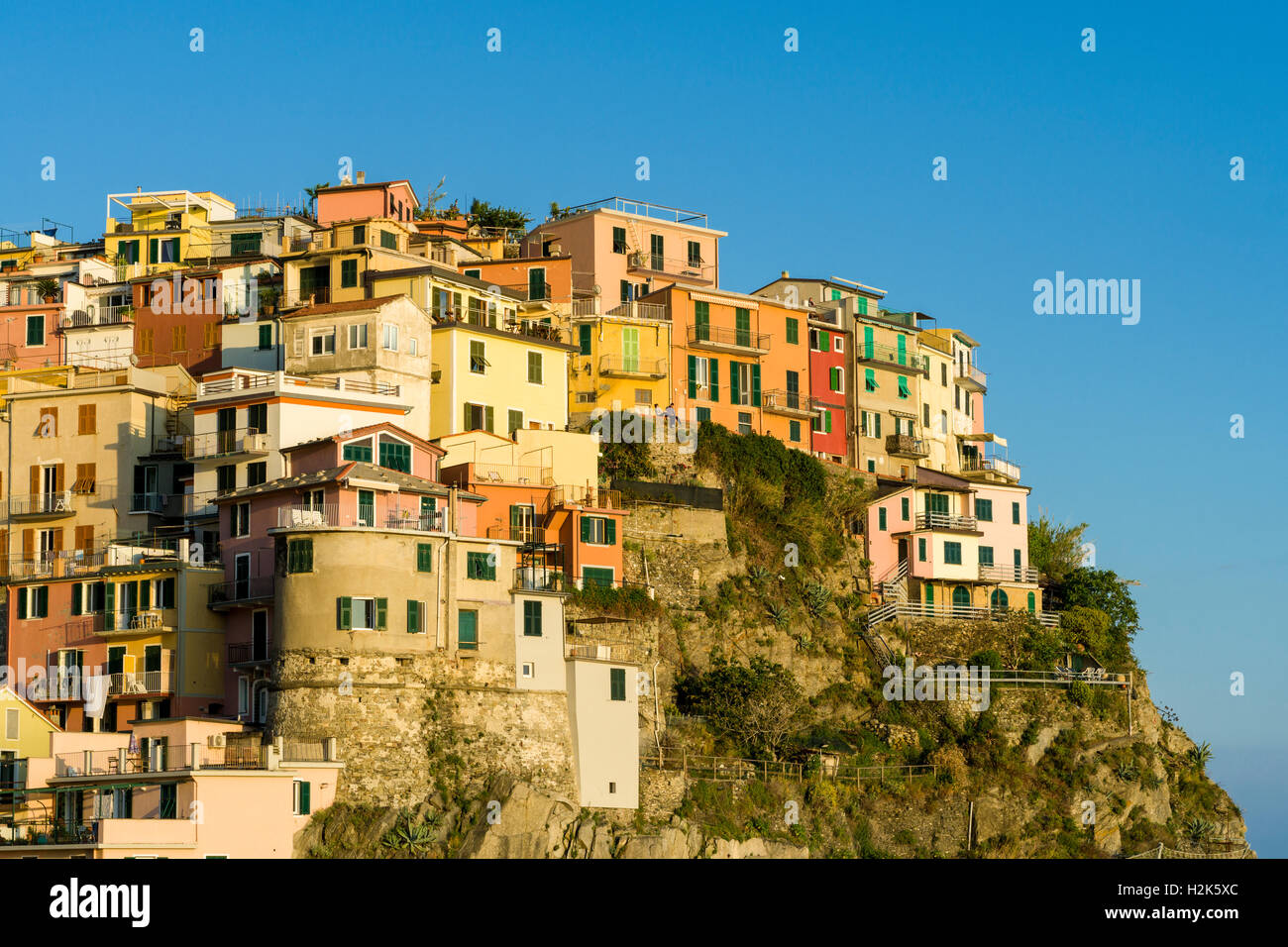 Case colorate di Manarola città stipati su una collina sulla costa del Mare Mediterraneo, Riomaggiore, Liguria, Italia Foto Stock