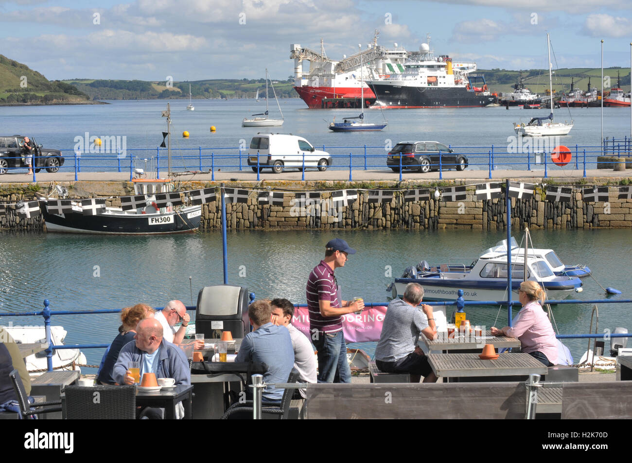 Turisti al di fuori di un pub di Falmouth con il dock in background Foto Stock