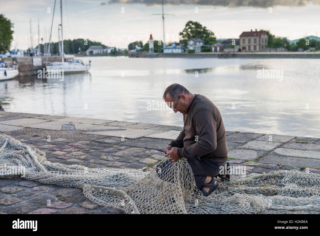 Fisherman riparazione di una rete da pesca in Honfleur, in Francia, in Europa. Foto Stock