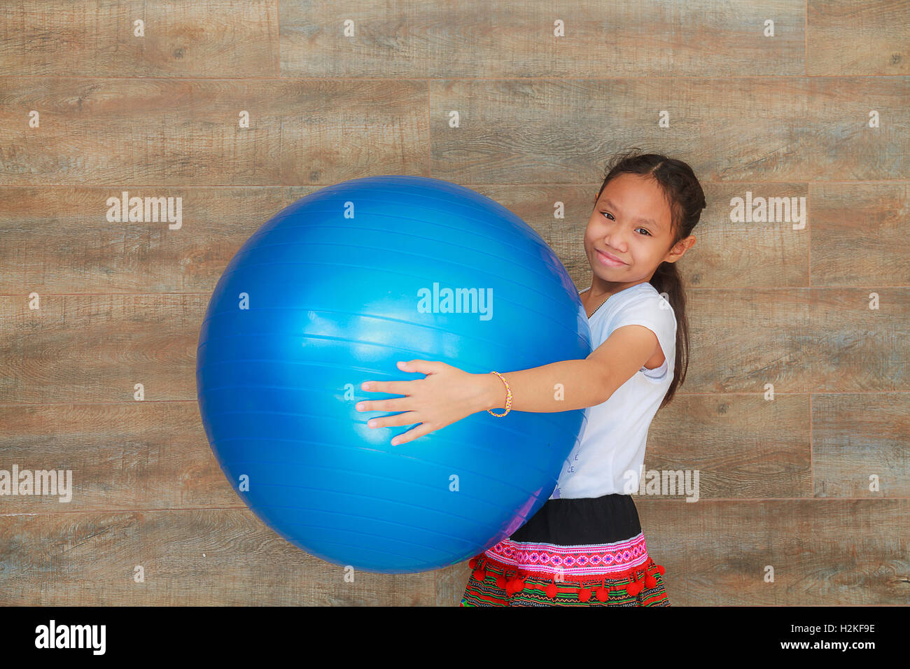 Ragazza bambino blu holding grande palla di gomma. Foto Stock