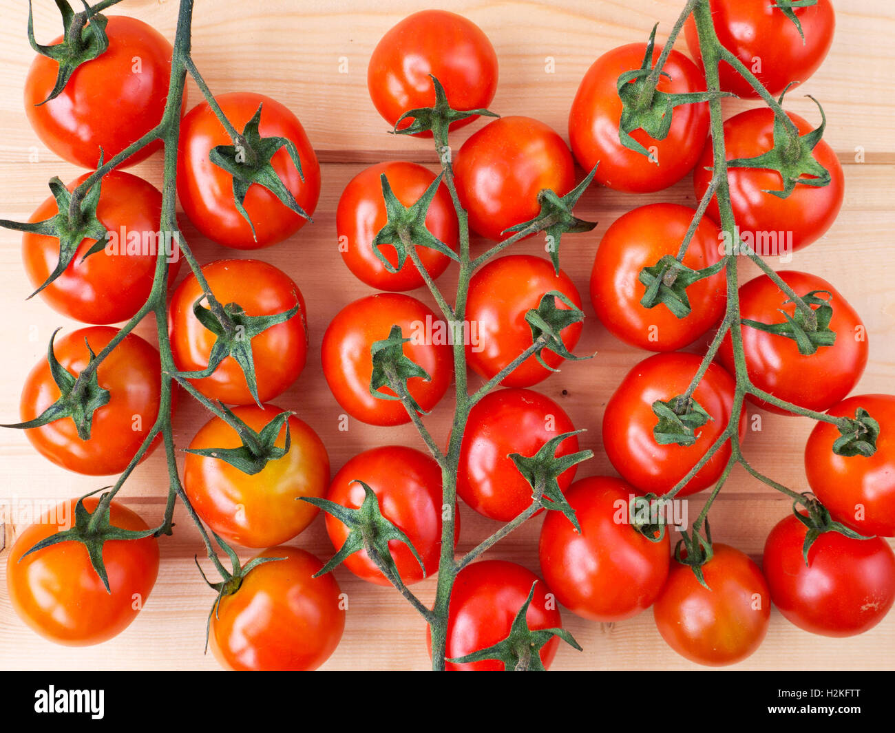 Tre grappoli di pomodoro sullo sfondo di legno Foto Stock