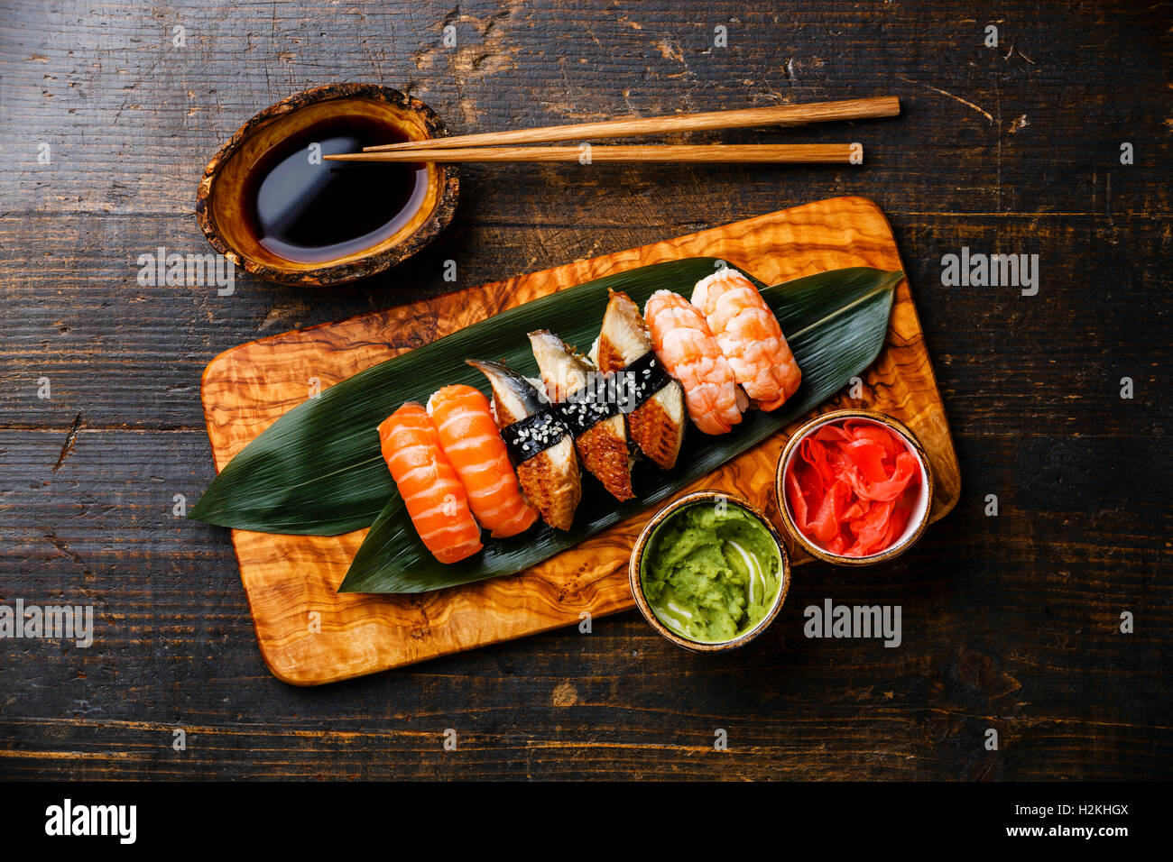 Il nigiri sushi Set su bambù foglia verde oliva su pannello di legno con salsa di soia su sfondo di legno Foto Stock