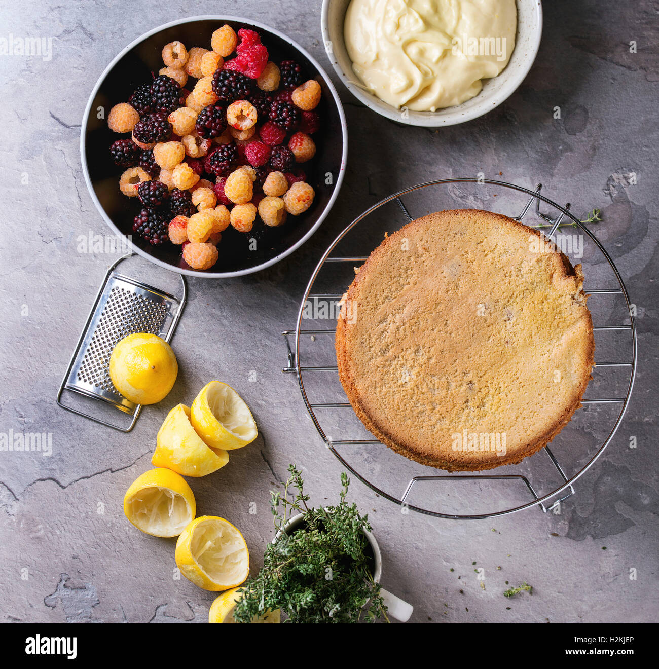 Bocce con gli ingredienti per la realizzazione di pan di spagna con crema di limone fresco colorato giallo rosso lampone e dewberries e timo, Foto Stock