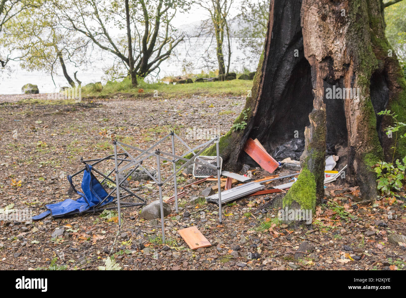 Campeggio selvaggio problemi - il comportamento antisociale e danni ambientali - sulla sponda occidentale del Loch Lomond Scozia - lettiera e detriti Albero bruciato Foto Stock