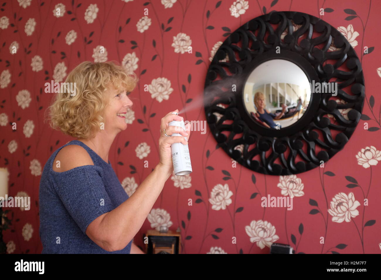 Donna fare pulizie domestiche faccende utilizzando profumatore bomboletta per aerosol a casa Foto Stock