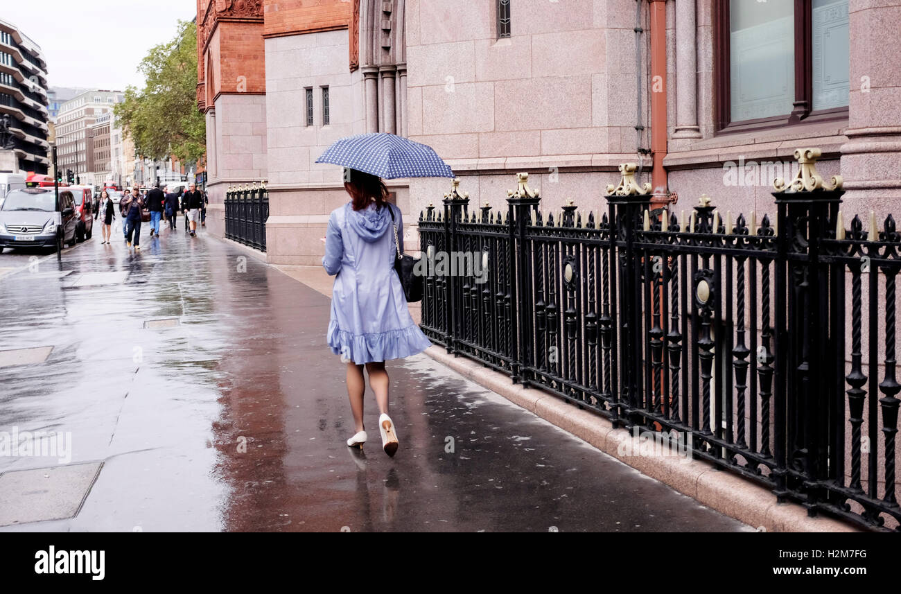 La donna a piedi dalla fotocamera sotto la pioggia con ombrello a High Holborn London REGNO UNITO Foto Stock