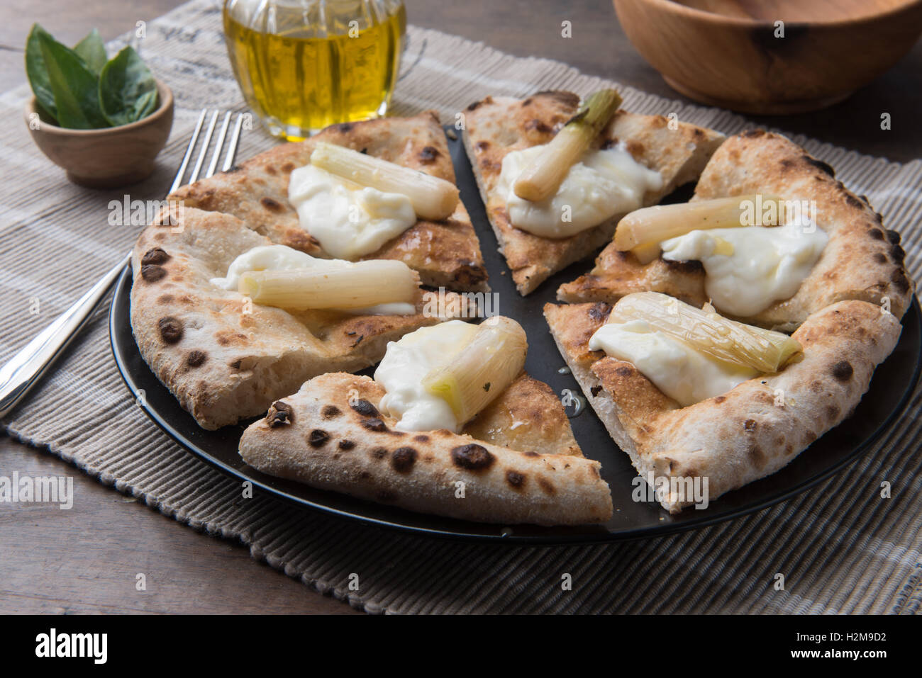 Fette di pizza gourmet con giovani cipolle e stracchino sulla vita ancora composizione Foto Stock