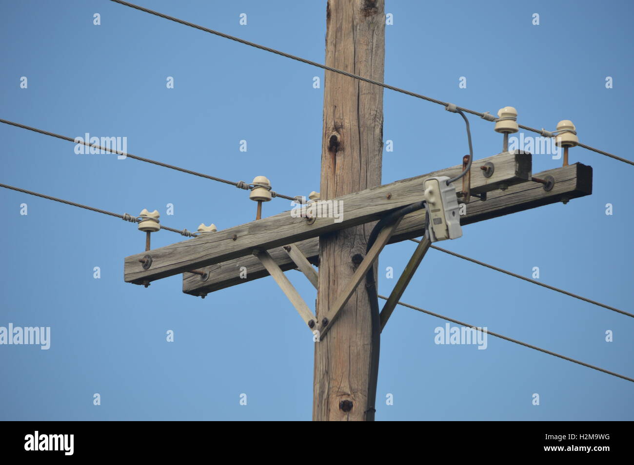 Palo del telefono con linee elettriche contro un cielo blu. Foto Stock