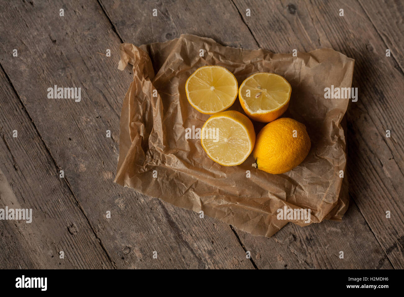 I limoni sulla carta da forno. fotografia di giallo dei limoni su carta pergamena fotografato su un pavimento di legno Foto Stock