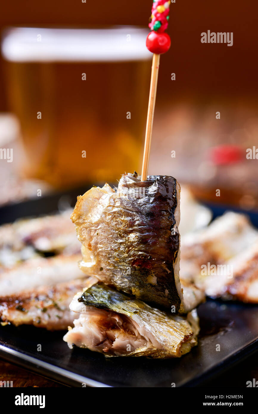 Ingrandimento di una piastra con un po' di spagnolo di filetti di sardine è servita come tapas, su una tavola in legno rustico, con un bicchiere di birra rinfrescante Foto Stock