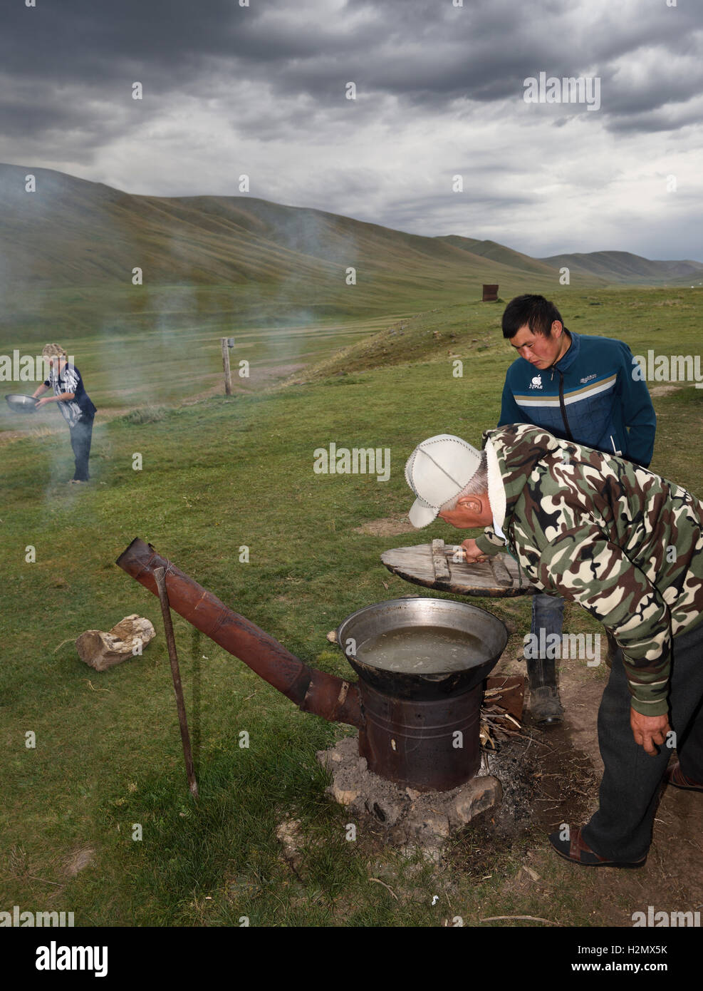 Famiglia kazako cottura carne su un forno esterno in estate pascoli di Plateau Assy Kazakistan Foto Stock