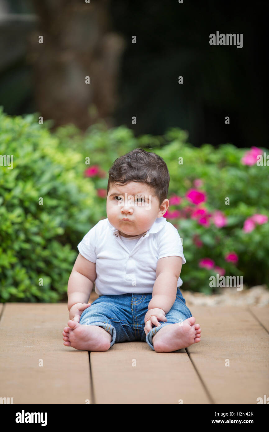 Carino piccolo bambino seduto all'aperto Foto Stock