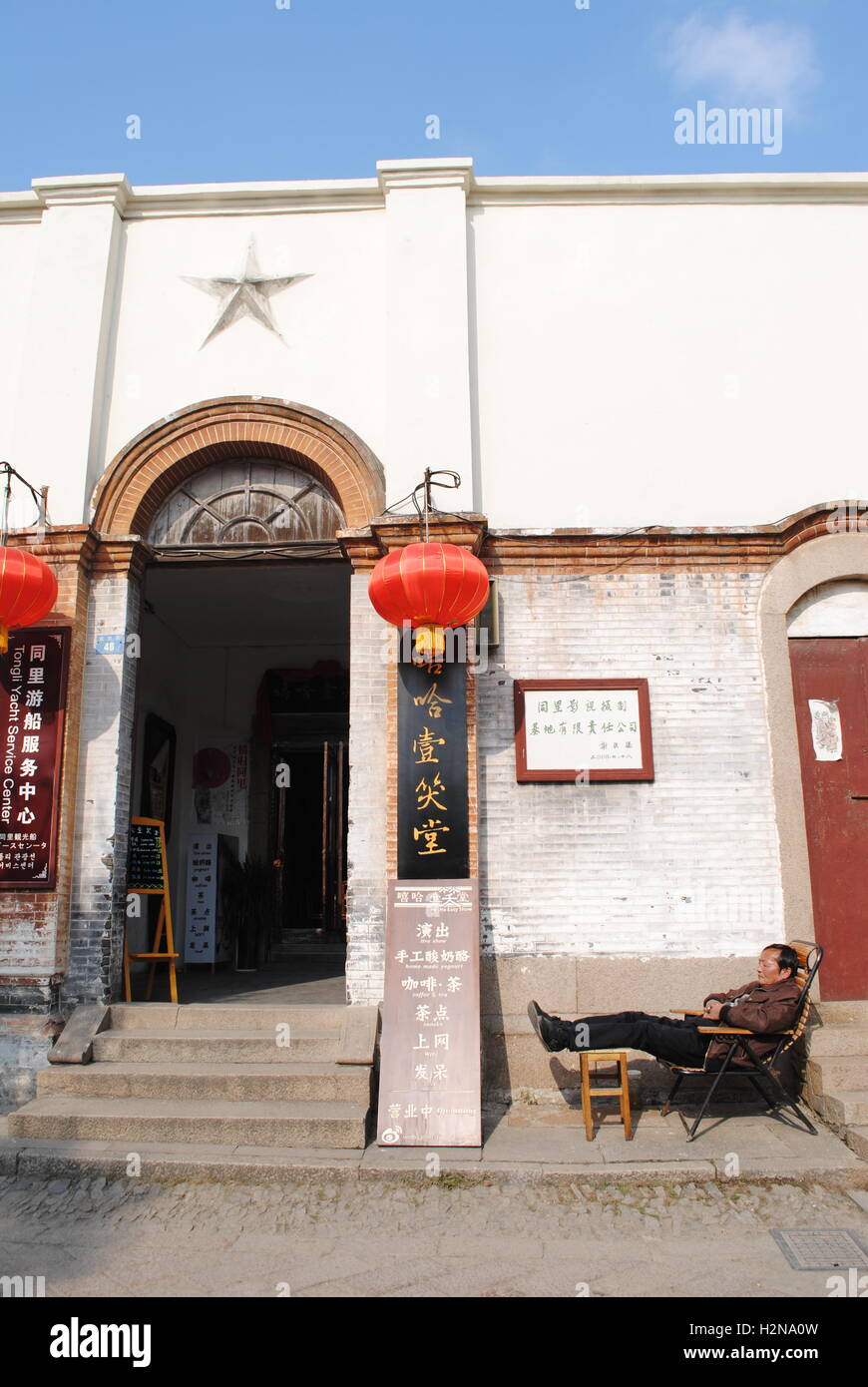 Un uomo cinese prende un pisolino fuori l'ingresso ad un funzionario cercando edificio in Tongli, una città d'acqua in Jiangsu, Cina. Foto Stock