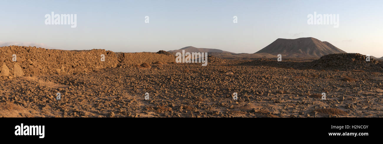 Fuerteventura Isole Canarie, Nord Africa, Spagna: muro di pietra e le montagne al tramonto sulla strada sterrata da Majanicho a Corralejo Foto Stock