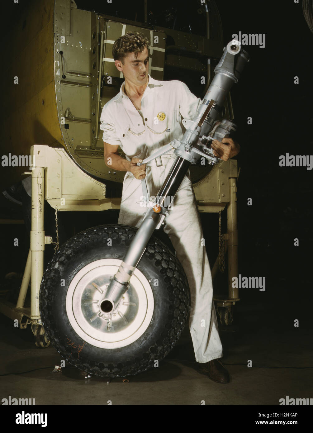 Worker che tiene la ruota anteriore e il dispositivo di atterraggio durante la produzione del bombardiere B-25, North American Aviation, Inc, Inglewood, California, USA, Alfred T. Palmer, USA Ufficio delle informazioni di guerra, ottobre 1942 Foto Stock