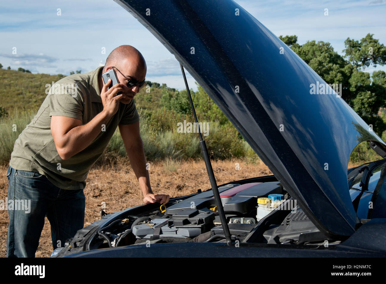 Close up di un ripartiti in automobile, il motore aperto, in una zona rurale e il conducente guardando il motore Foto Stock
