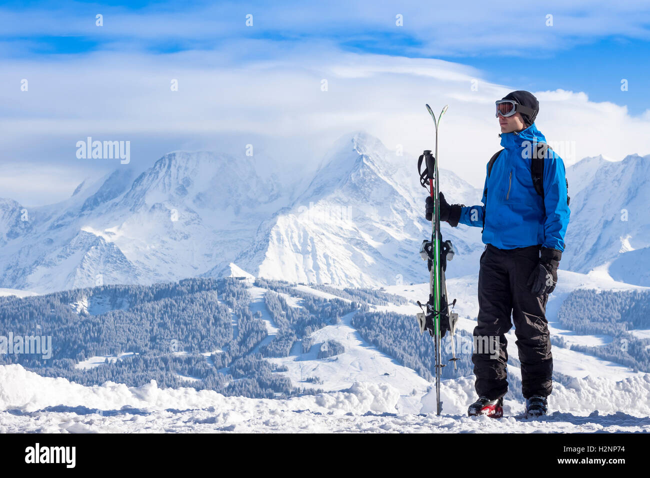 Sciatore tenendo gli sci e guardando bella coperta di neve valle Foto Stock