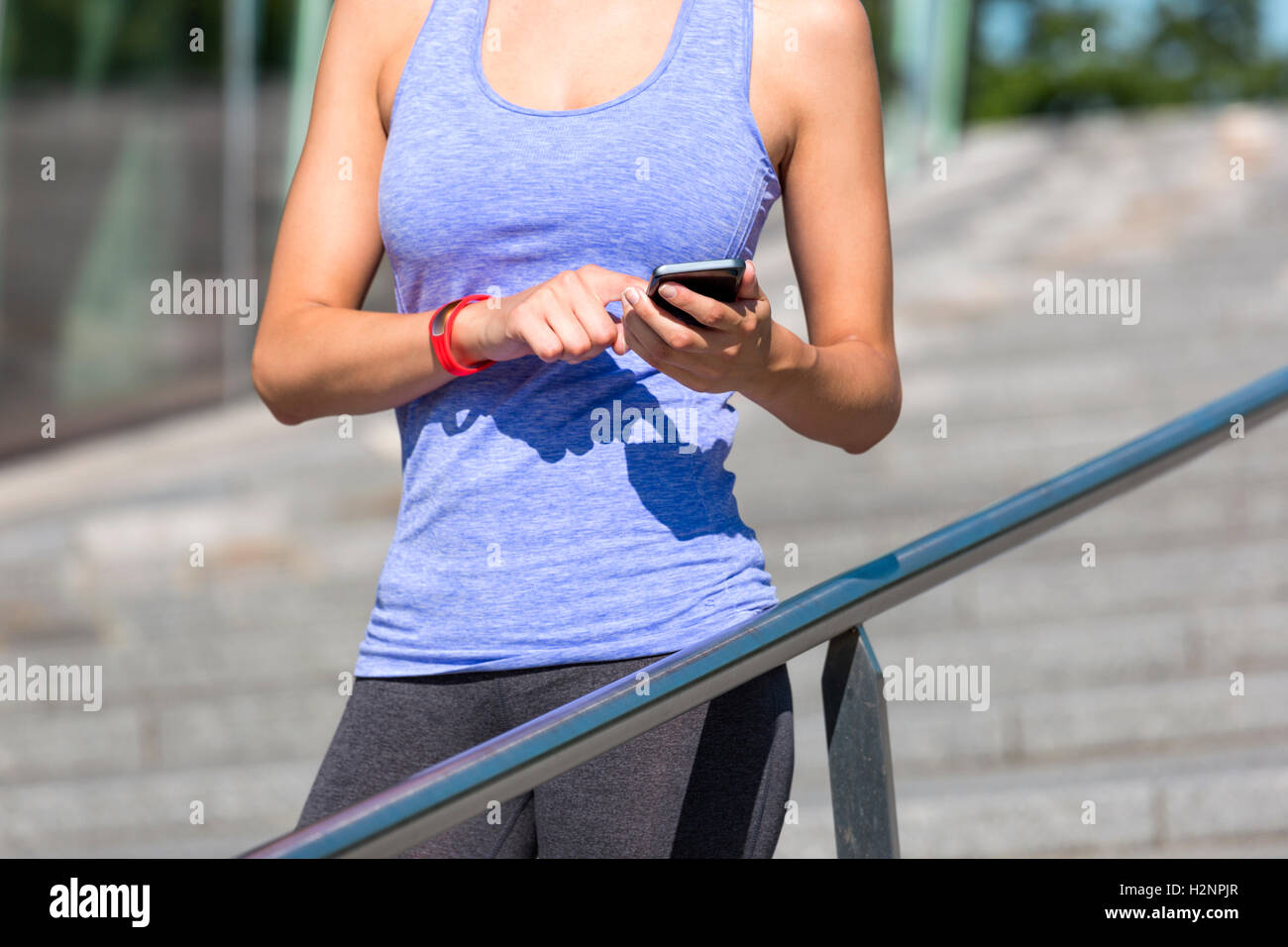 Donna sportive poggia su un corrimano e verifica la sua idoneità risultati su uno smartphone. Foto Stock