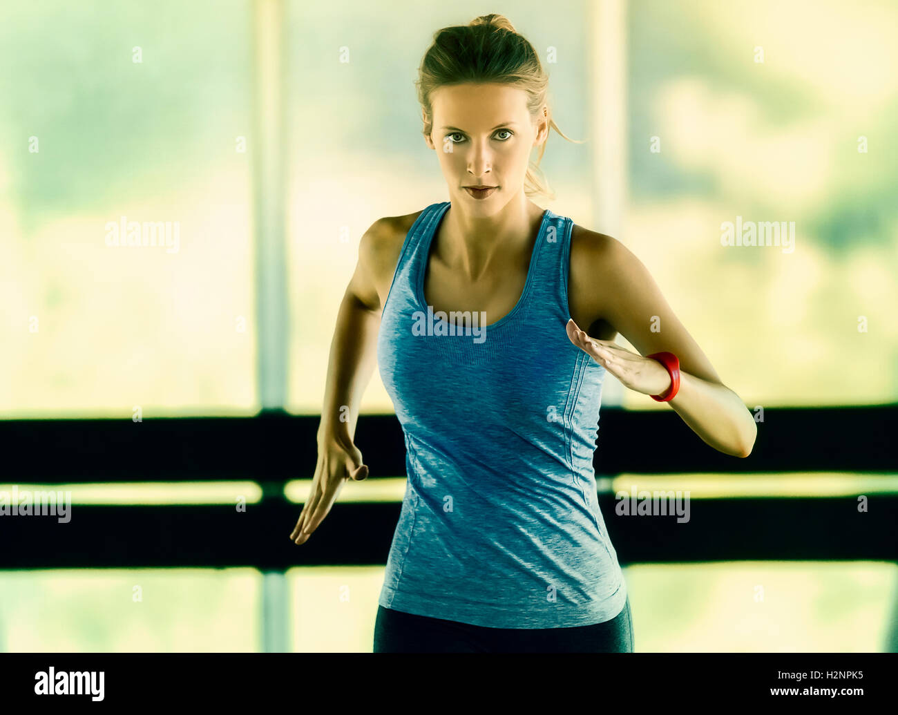 Energico che eseguono allenamento di una giovane donna in un vetro incorniciato corridoio. Indossa un fitness tracker sul suo braccio sinistro. Foto Stock
