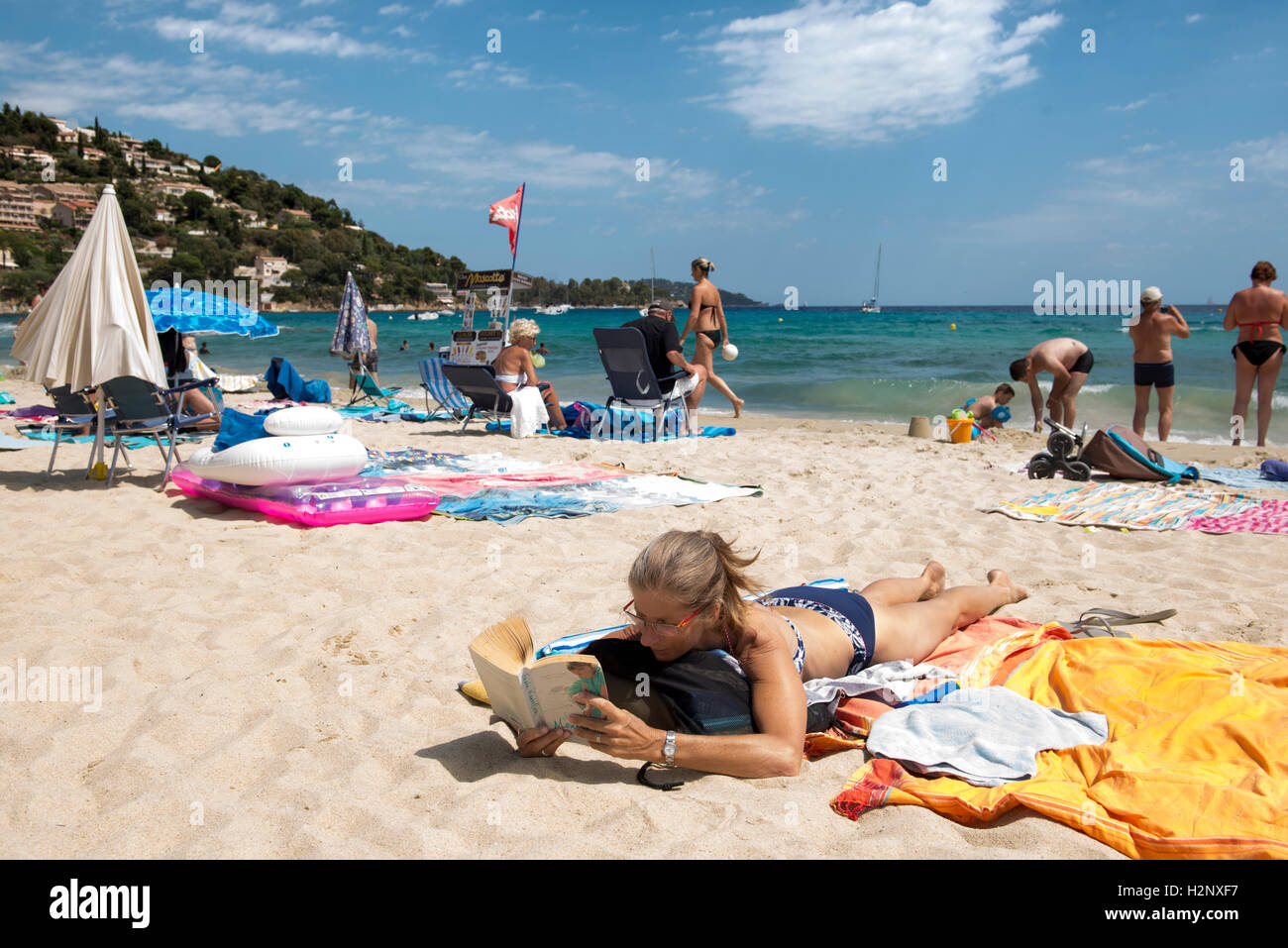 Donna sdraiata sulla spiaggia la lettura di un libro, closeup, Le Lavandou area, Regione Provenza-Alpi-Costa Azzurra, Francia Foto Stock