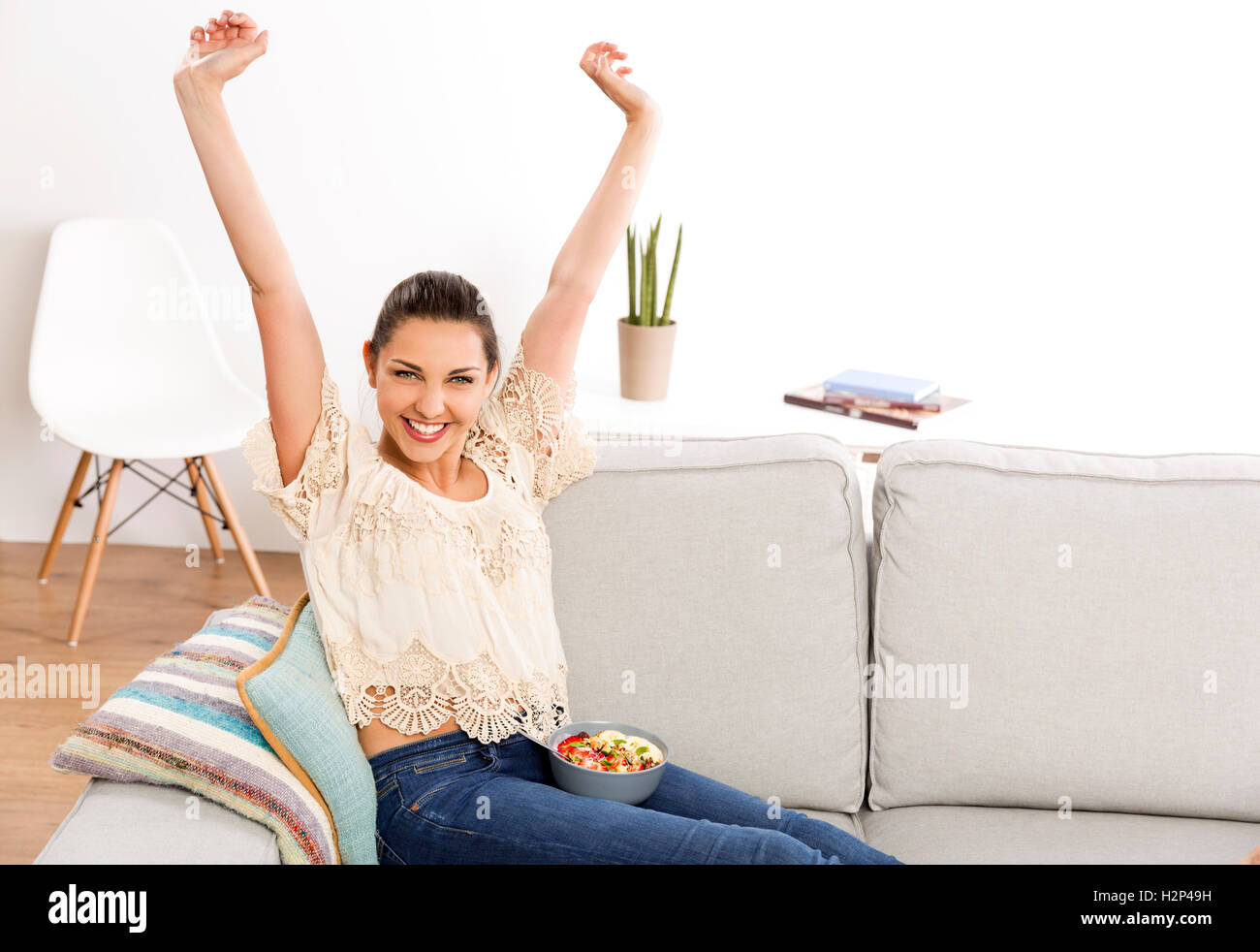 Bella donna felice a casa a mangiare una ciotola sani Foto Stock