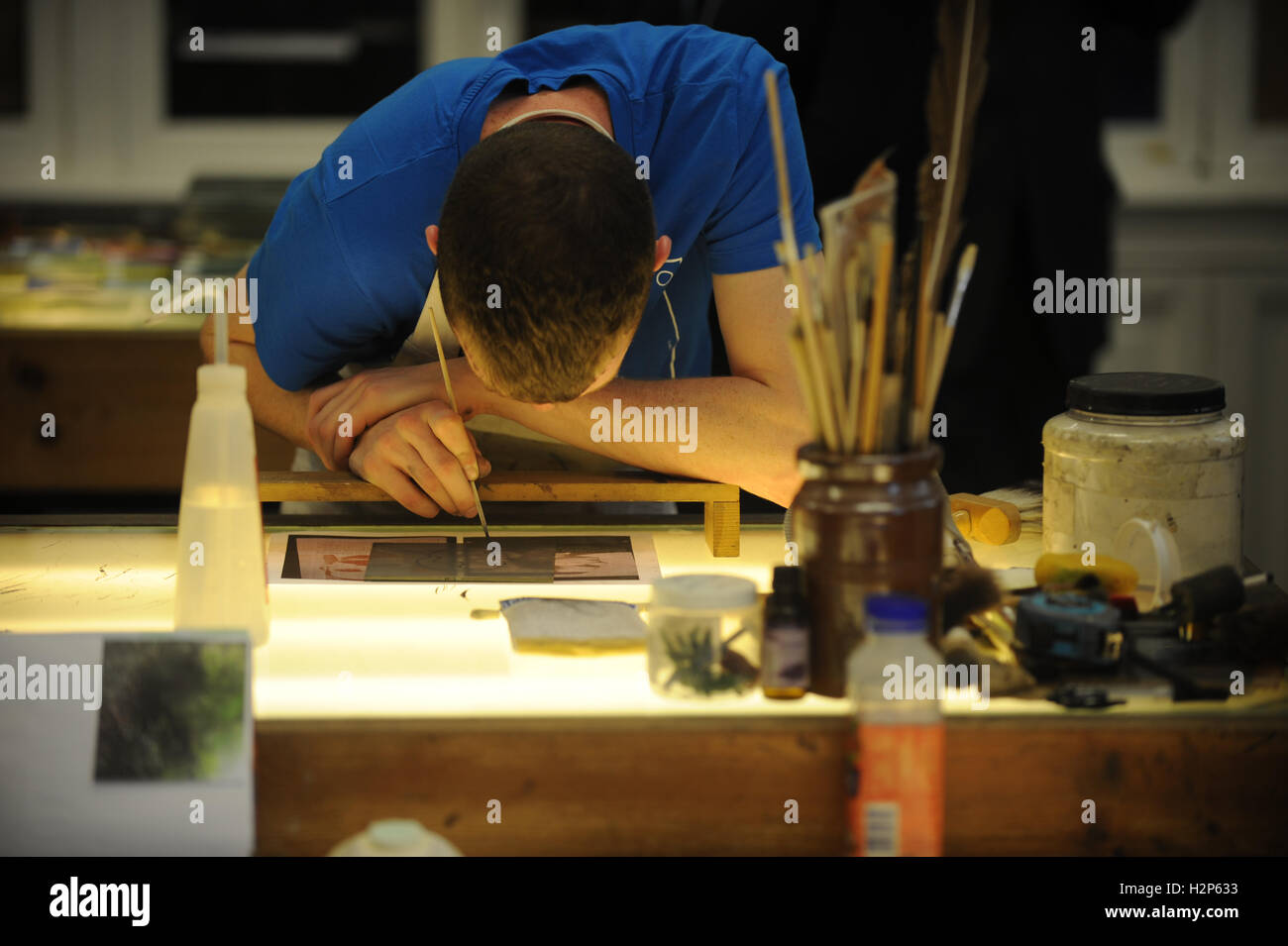 Uno studente di design lavora duro sul taglio di una forma,, tracciando così come essa giace su una lightbox in un collegio di classe. Foto Stock