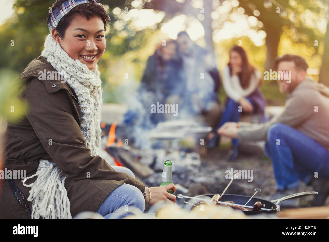 Ritratto di donna sorridente di bere birra con gli amici a fuoco Foto Stock