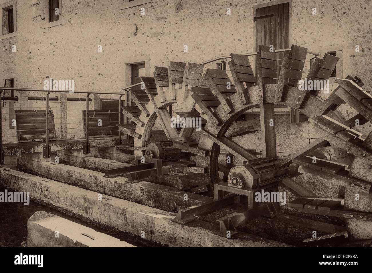 Vecchie ruote di un mulino ad acqua. In stile vintage foto. Aggiunta di grano per dare una vecchia foto effetto. Foto Stock